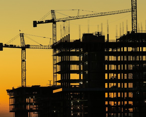 Construction site at sunset with cranes silhouetted